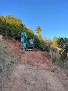 Excavadora turquesa en ladera
